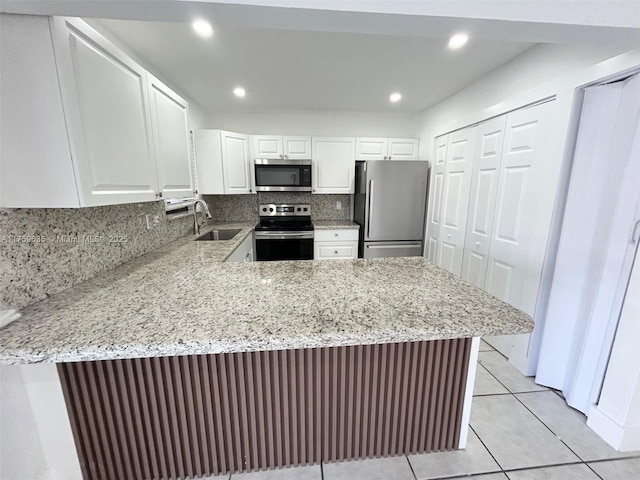 kitchen featuring a sink, a peninsula, light stone countertops, and stainless steel appliances