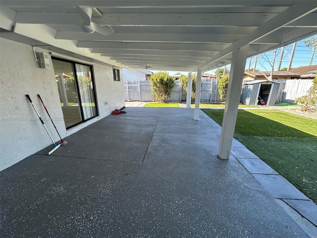 view of patio / terrace featuring an outdoor structure, ceiling fan, and fence