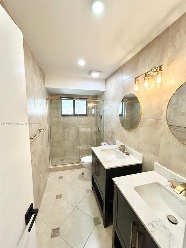 bathroom with tile walls, a stall shower, tile patterned floors, and a sink