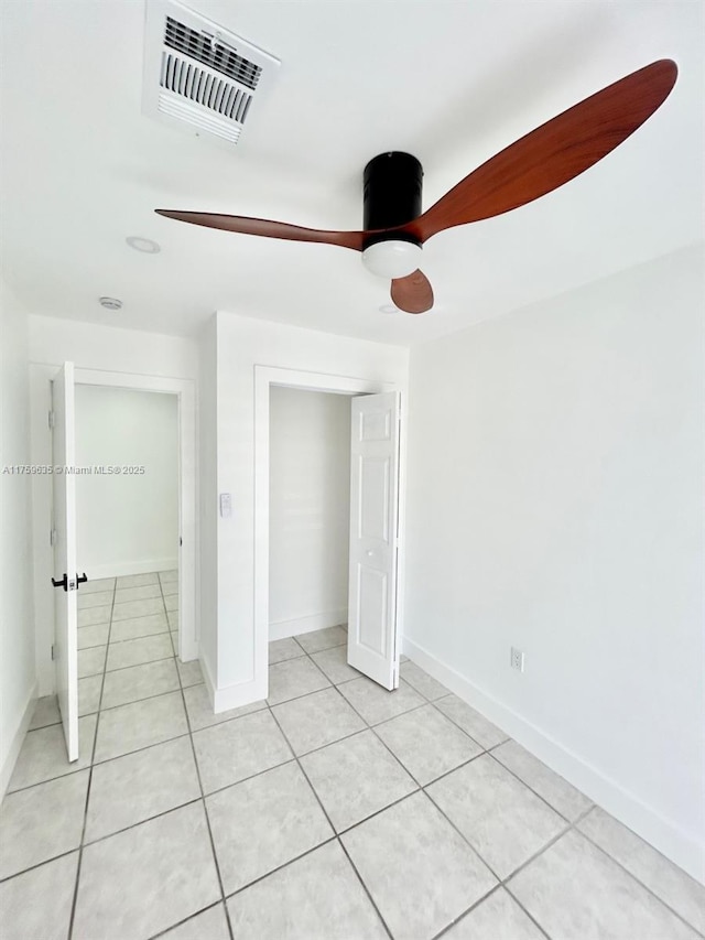 unfurnished bedroom featuring light tile patterned flooring, visible vents, a ceiling fan, and baseboards