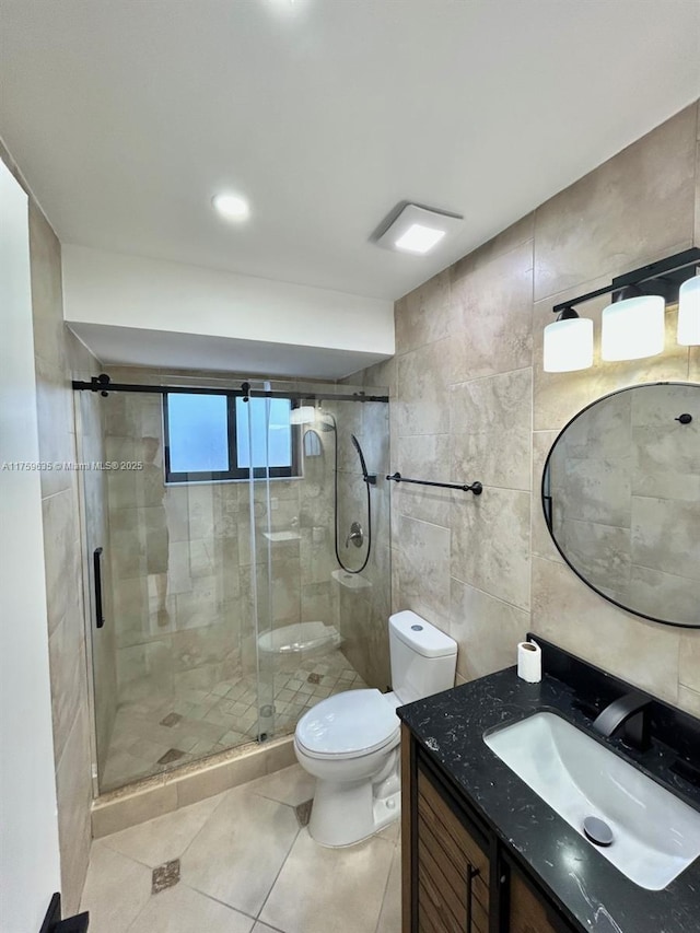 bathroom with vanity, tile patterned flooring, a shower stall, tile walls, and toilet