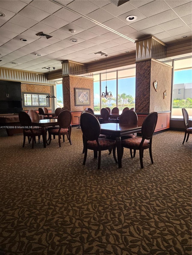 dining area with dark colored carpet, visible vents, and a paneled ceiling