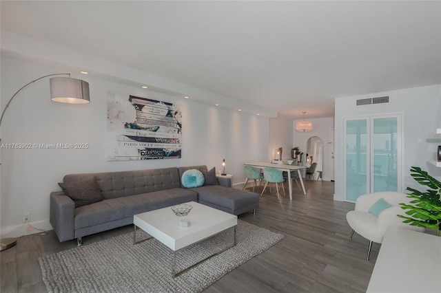 living room with visible vents, baseboards, recessed lighting, wood finished floors, and arched walkways