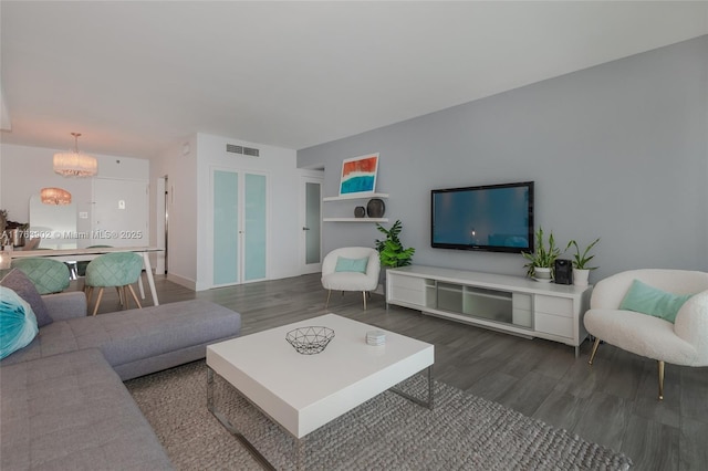 living room with a notable chandelier, visible vents, and wood finished floors