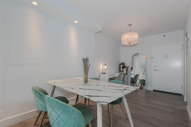 dining area featuring recessed lighting, baseboards, arched walkways, and wood finished floors