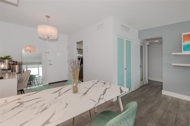 dining space featuring visible vents, baseboards, and wood finished floors