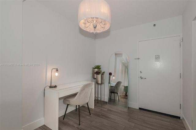 home office featuring arched walkways, an inviting chandelier, baseboards, and wood finished floors