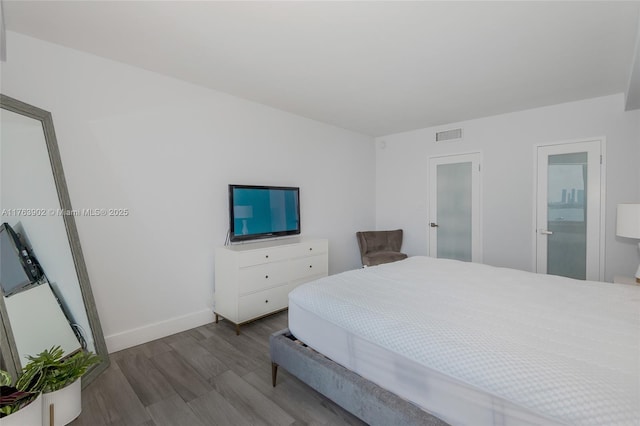 bedroom with wood finished floors, visible vents, and baseboards