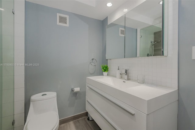 full bath with toilet, tasteful backsplash, wood finished floors, and visible vents