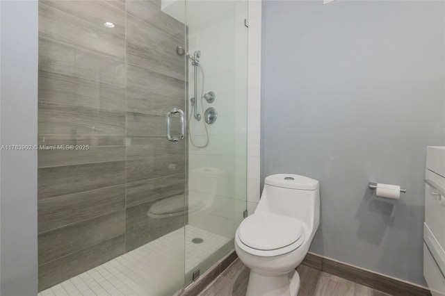 bathroom with a shower stall, toilet, and baseboards