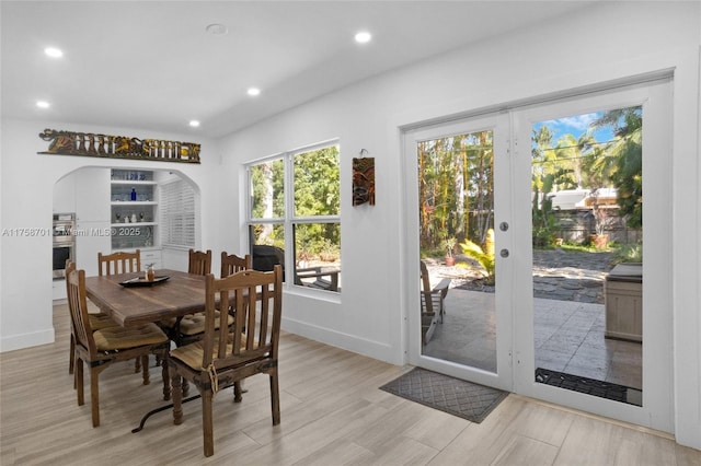 dining room featuring light wood finished floors, baseboards, recessed lighting, french doors, and arched walkways