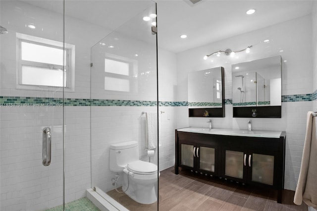 full bath with double vanity, a sink, a shower stall, tile walls, and toilet