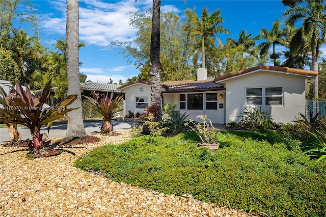 view of front of property with stucco siding, a chimney, and a tile roof