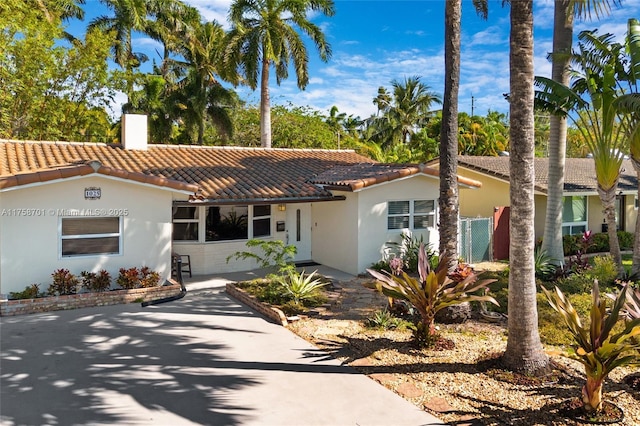 mediterranean / spanish-style home featuring stucco siding, a chimney, and a tile roof