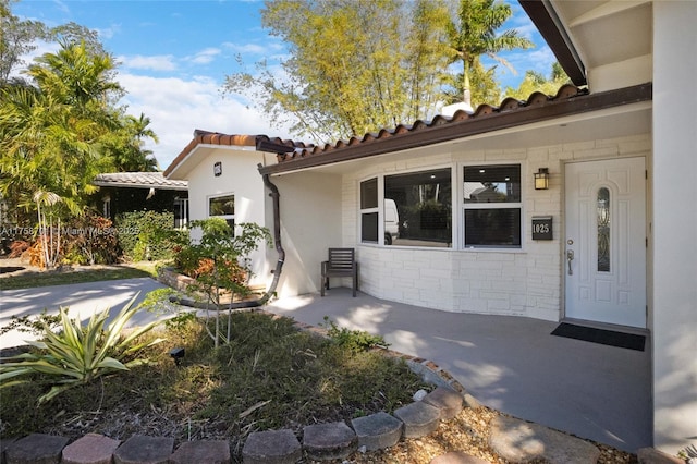 view of exterior entry featuring stucco siding, stone siding, and a tiled roof