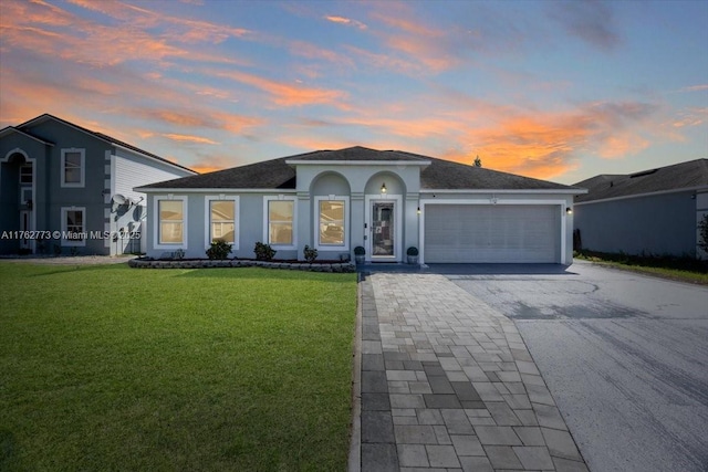 view of front facade with stucco siding, a front lawn, driveway, an attached garage, and a shingled roof