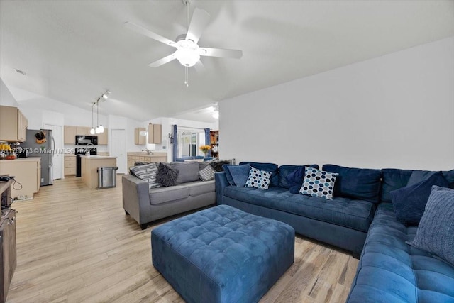 living room with light wood-style flooring, ceiling fan, and vaulted ceiling