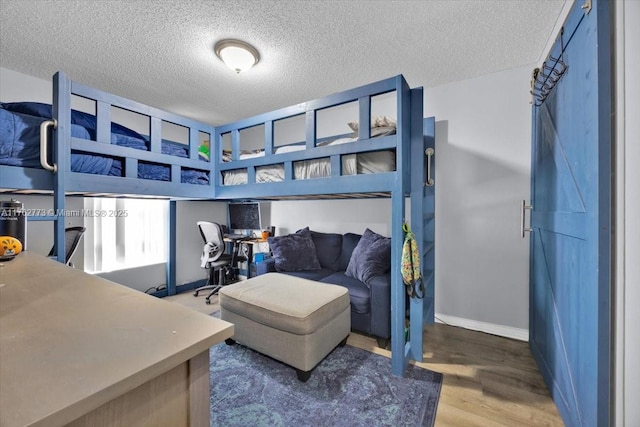 bedroom with a textured ceiling, baseboards, and wood finished floors