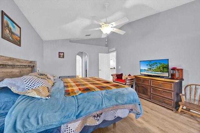 bedroom with visible vents, lofted ceiling, light wood-style flooring, arched walkways, and a ceiling fan