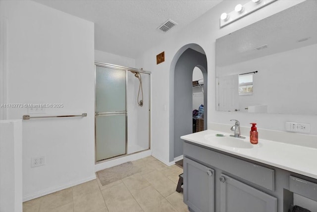 bathroom featuring visible vents, a stall shower, a textured ceiling, and vanity