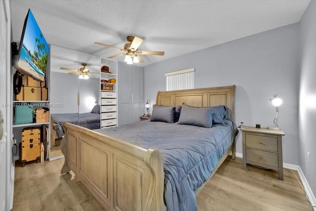 bedroom featuring a ceiling fan, baseboards, light wood finished floors, and a textured ceiling