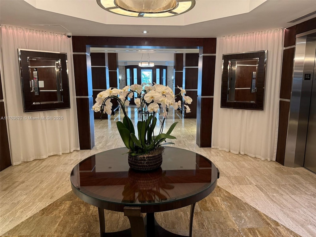 corridor with elevator, french doors, and a tray ceiling