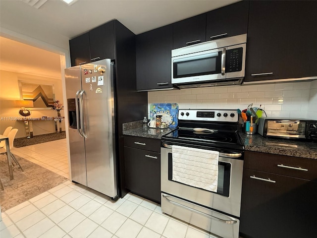 2451 Brickell Ave Unit 20N, Miami, FL 33129 - kitchen featuring appliances with stainless steel finishes, dark cabinetry, decorative backsplash, light tile patterned floors, and dark stone countertops
