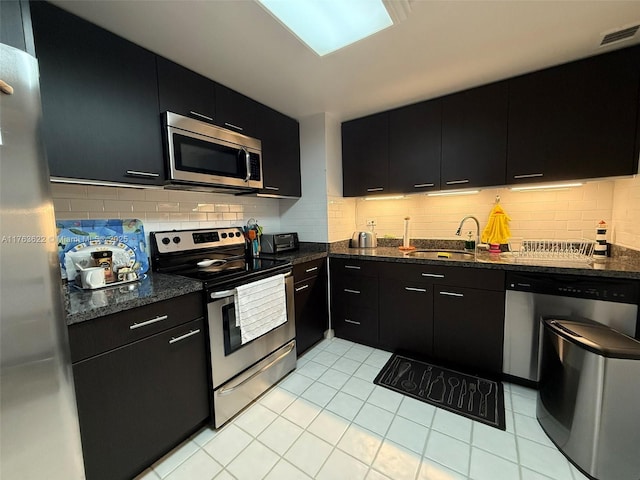 2451 Brickell Ave Unit 20N, Miami, FL 33129 - kitchen with stainless steel appliances, dark cabinets, a sink, tasteful backsplash, and light tile patterned floors
