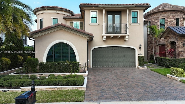 mediterranean / spanish-style house featuring a balcony, stucco siding, a tiled roof, and a garage