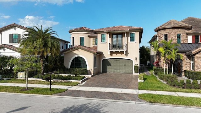 mediterranean / spanish home featuring a balcony, an attached garage, stucco siding, a tiled roof, and decorative driveway