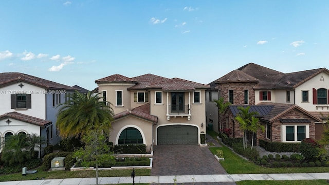 view of front of house with stucco siding, a garage, driveway, and a tile roof