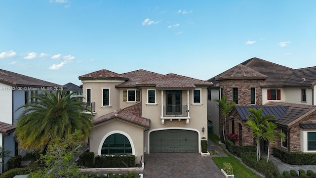 view of front of property with stucco siding, driveway, a tile roof, and a garage