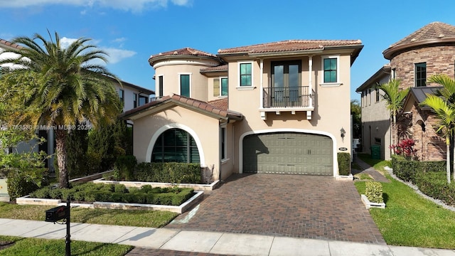 mediterranean / spanish-style home featuring stucco siding, a tile roof, decorative driveway, an attached garage, and a balcony