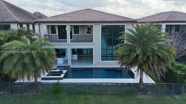 back of house featuring stucco siding, a patio, a fenced backyard, a balcony, and a tiled roof