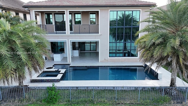 back of property featuring stucco siding, fence private yard, a tile roof, and a balcony