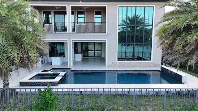 rear view of house with fence, stucco siding, a balcony, a patio area, and a ceiling fan