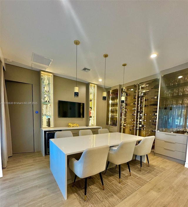 dining area with light wood-type flooring, visible vents, beverage cooler, and recessed lighting