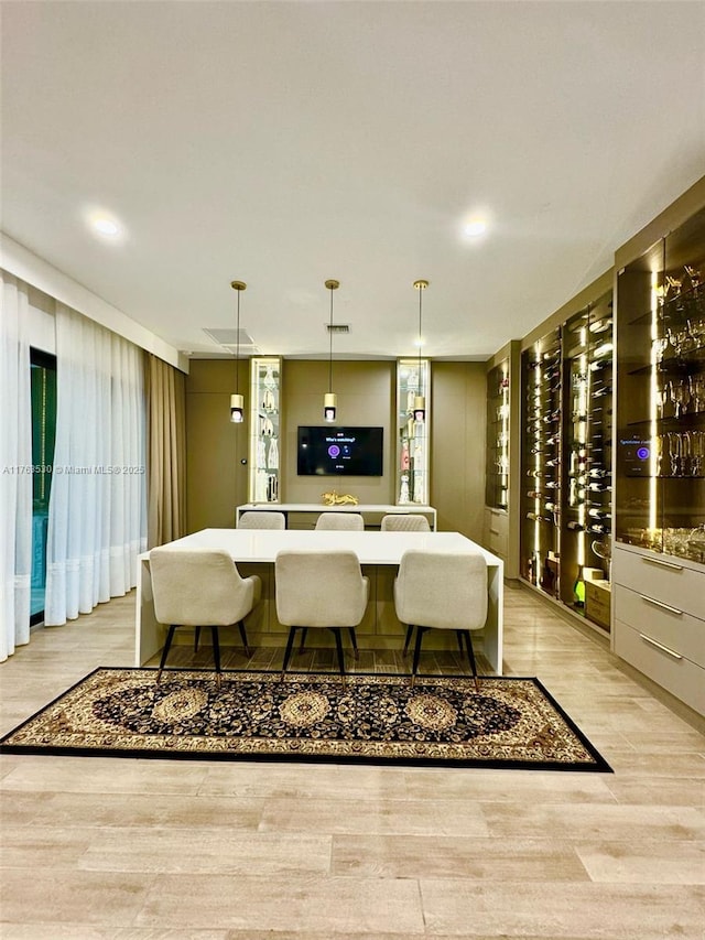 bar featuring light wood finished floors and decorative light fixtures