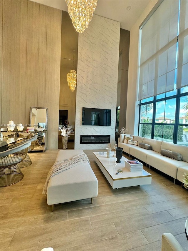 living room featuring a high ceiling, a notable chandelier, wood finished floors, and a premium fireplace