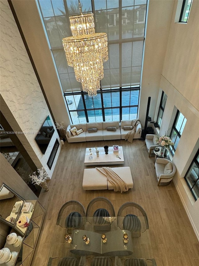 unfurnished living room with a high ceiling, an inviting chandelier, and wood finished floors