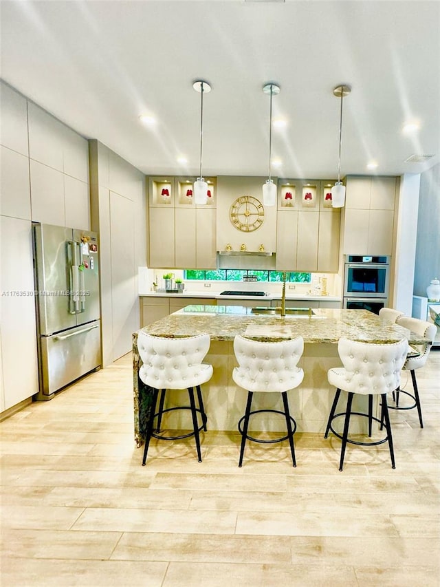 kitchen with light wood-style flooring, appliances with stainless steel finishes, a breakfast bar area, and a sink