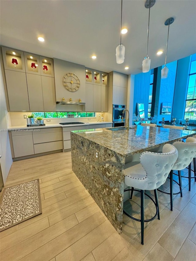 kitchen featuring a breakfast bar area, a sink, oven, modern cabinets, and light wood-type flooring