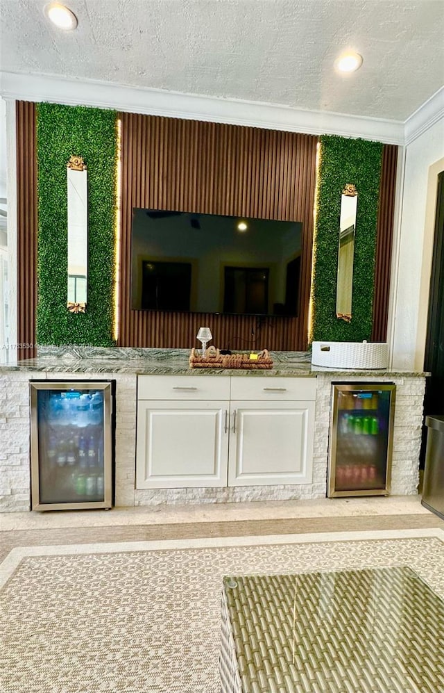 bar featuring a textured ceiling, beverage cooler, and ornamental molding