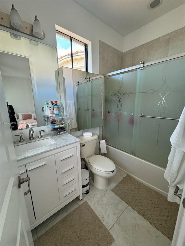 full bath with vanity, toilet, and bath / shower combo with glass door