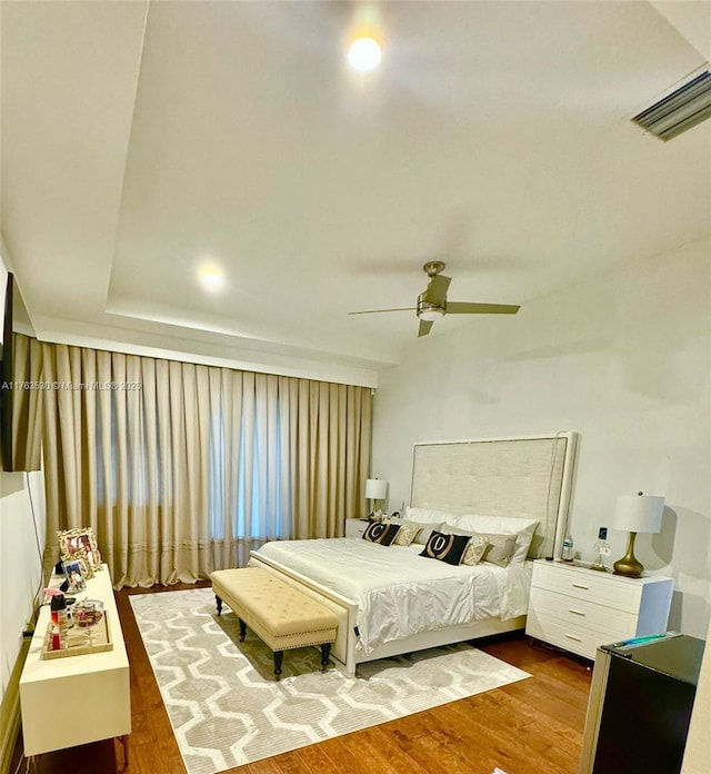 bedroom with ceiling fan, visible vents, and wood finished floors