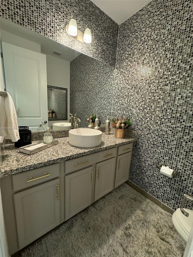 full bath with visible vents, toilet, tile walls, and vanity