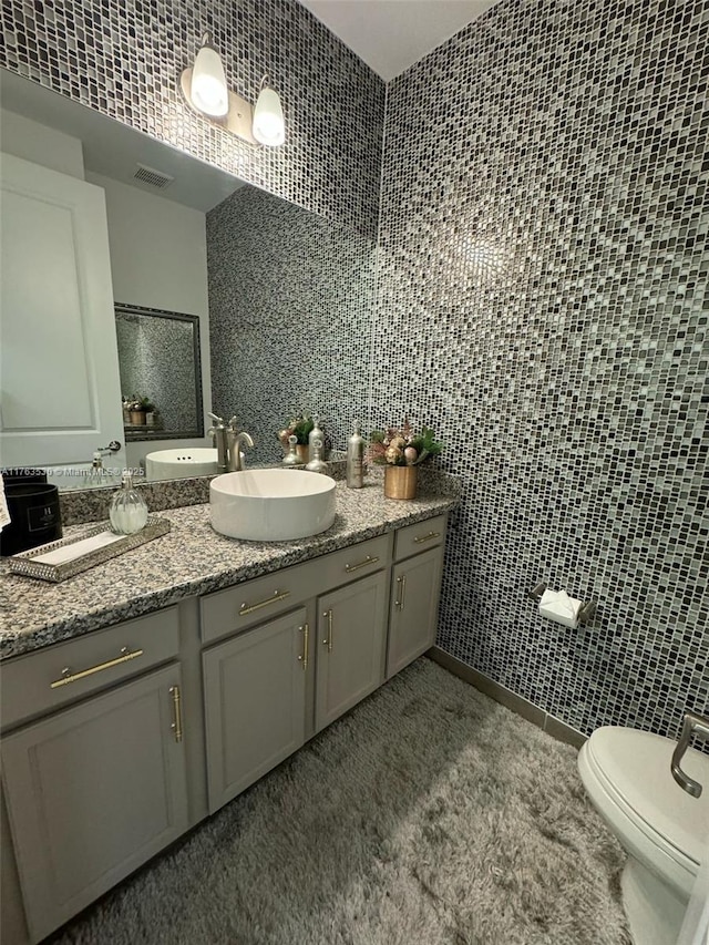 bathroom with visible vents, toilet, tile walls, and vanity