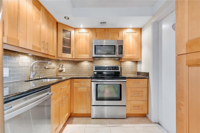 kitchen featuring light tile patterned floors, visible vents, dark stone counters, a sink, and stainless steel appliances