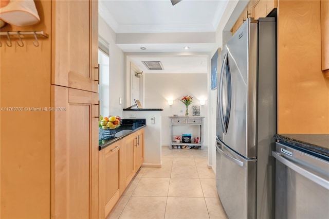 kitchen with light brown cabinets, ornamental molding, light tile patterned floors, dark stone countertops, and freestanding refrigerator