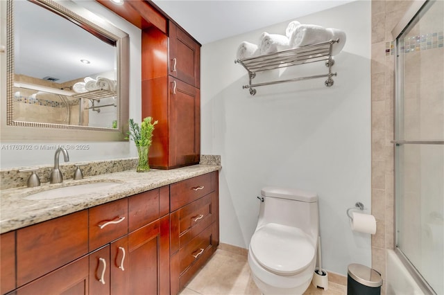 full bath featuring vanity, baseboards, bath / shower combo with glass door, tile patterned floors, and toilet